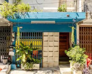 a store front with a blue awning and plants at Bang Chak Studio in Bangkok