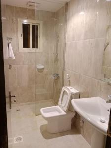 a bathroom with a toilet and a sink and a shower at فندق اوتاد البدر الششه in Al Khansāk