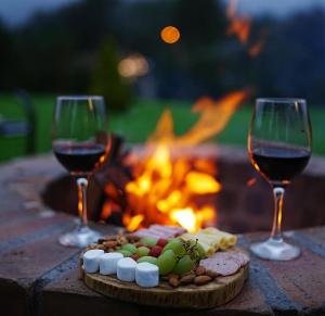 two glasses of wine and a plate of food next to a fire pit at Glamping Al Pie del Cerro in San Fernando