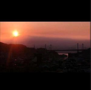 una puesta de sol sobre una ciudad con un puente en el fondo en O19 Tea Celemony Villa, en Onomichi 5 fotos más