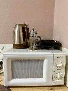 a microwave with a tea pot on top of it at Midtown Cozy Apartment in Tirana +3 photos