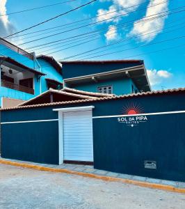 a blue building with a garage and a sign on it at Sol da pipa - suítes in Pipa +10 photos