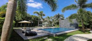 Nua Tone Pool Villa I Mountain View I Bangtao Beach في Ban Thalat Choeng Thale: مسبح في ساحة فيها نخيل