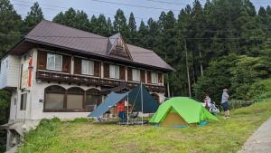 a house with a group of tents in front of it at Red Gate Lodge in Kijimadaira