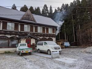 a house with two cars parked in front of it at Red Gate Lodge in Kijimadaira