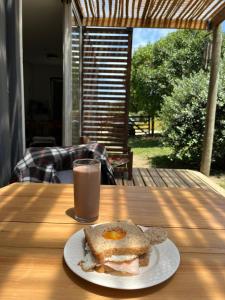 a plate with an egg sandwich and a glass of milk at La Pausa Container House in Manantiales