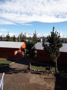 a couple of buildings with trees in front of them at Cabañas San Benito in Los Antiguos