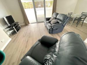 a living room with a black leather couch and chairs at Bunbury Glen Iris Retreat D in Glen Iris