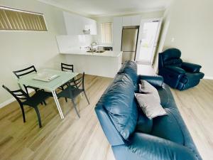 a living room with a blue leather couch and a table at Bunbury Glen Iris Retreat D in Glen Iris