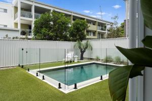 a swimming pool with a glass fence around it at Holiday Haven on Spoonbill Pet Friendly with Pool in Kingscliff