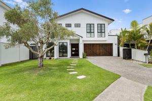 a white house with a tree in the yard at Holiday Haven on Spoonbill Pet Friendly with Pool in Kingscliff