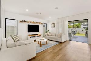a living room with two couches and a tv at Holiday Haven on Spoonbill Pet Friendly with Pool in Kingscliff