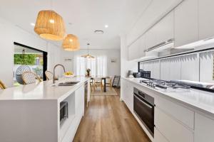 a kitchen with white cabinets and a counter top at Holiday Haven on Spoonbill Pet Friendly with Pool in Kingscliff