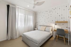 a bedroom with a bed and a desk and a window at Holiday Haven on Spoonbill Pet Friendly with Pool in Kingscliff +36 photos