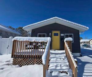 ein kleines Haus mit gelber Tür im Schnee in der Unterkunft Renovated 2BR Home Near Notre Dame & Eddy St in South Bend