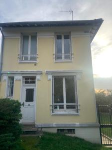 een geel huis met twee ramen en een deur bij Petite Maison in Châtenay-Malabry