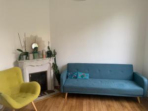 een woonkamer met een blauwe bank en een stoel bij Petite Maison in Châtenay-Malabry