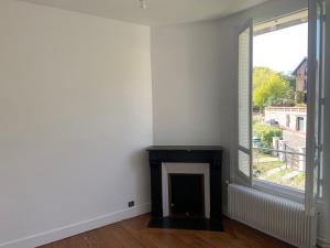 een witte kamer met een open haard en een raam bij Petite Maison in Châtenay-Malabry