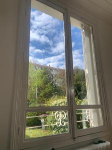 een raam met uitzicht op een gebouw bij Petite Maison in Châtenay-Malabry