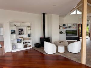 - un salon avec deux chaises blanches et une cheminée dans l'établissement Private Beachfront Haven with Starlink & Panoramic Views, à Kerikeri