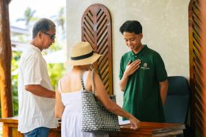 Una mujer con sombrero y dos hombres de pie alrededor de una mesa. en Bellamar Villas, en El Nido 21 fotos más