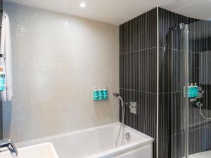 a bathroom with a bath tub and a shower at Novotel Suites Malaga Centro in Málaga