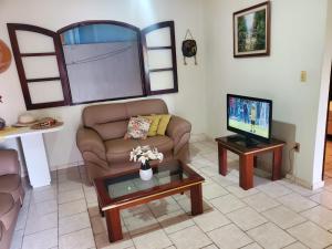 een woonkamer met een bank en een tv bij Casa da Vila in Saquarema