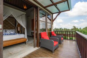 a bedroom with a bed and two chairs on a balcony at Uma Stana Villa in Ubud