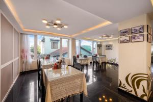 a dining room with tables and chairs and windows at Vina Spa Hotel in Hue
