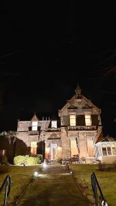 uma casa velha à noite com as luzes acesas em West Coates Mansion em Edinburgo