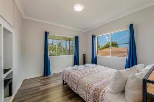 ein Schlafzimmer mit einem Bett und zwei Fenstern in der Unterkunft 64 Bathurst Street in Elliott Heads