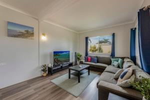 ein Wohnzimmer mit Sofa und Fernseher in der Unterkunft 64 Bathurst Street in Elliott Heads