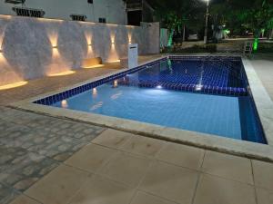 a swimming pool at night with lights on it at aconchegante e tranquila in Parnamirim
