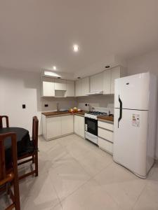 een keuken met een witte koelkast en een tafel bij Dpto lo de Bruno in Santa Clara del Mar