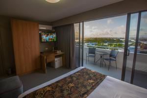 Habitación de hotel con cama y balcón con TV. en Gladstone Reef Hotel Motel, en Gladstone