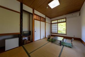 a room with a table and a tv and a window at YUPOPPO Hakone in Hakone