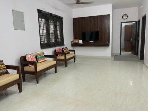un salon avec deux chaises et une télévision dans l'établissement Raj Nivas, à Mayiladuthurai