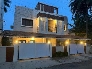 une maison avec des clôtures blanches devant elle dans l'établissement Raj Nivas, à Mayiladuthurai