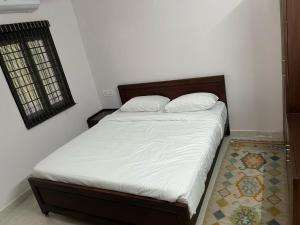une chambre avec un lit avec des draps blancs et une fenêtre dans l'établissement Raj Nivas, à Mayiladuthurai