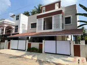 une maison avec des clôtures blanches devant elle dans l'établissement Raj Nivas, à Mayiladuthurai