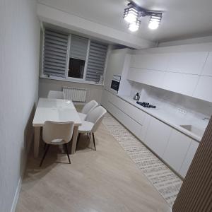 - une cuisine avec une table blanche et des chaises blanches dans l'établissement Apartament Buiucani Alba Iulia, à Chişinău