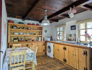 a kitchen with wooden cabinets and a table and a sink at The Village Cottage in Ocna de Jos