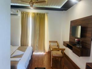 una camera con letto, TV e sedia di Simran Aura Resort a Dehradun