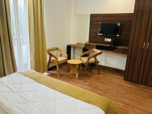 una camera d'albergo con un letto, due sedie e una TV di Simran Aura Resort a Dehradun
