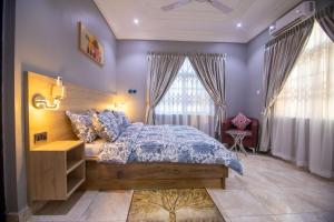 ein Schlafzimmer mit einem großen Bett mit lila Wänden und Fenstern in der Unterkunft Glenwood Apartment in Amrahia