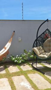 a hammock and a chair next to a wall at La casa de Luna in Guaibim