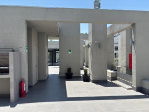 Un pasillo vacío de un edificio con un extintor rojo. en A pasos del metro Steps away from the subway, en Santiago