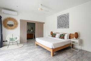 ein Schlafzimmer mit einem Bett, einem Spiegel und einem Stuhl in der Unterkunft Villa Nirvana, 3 Bedrooms, Chaweng Noi in Koh Samui  + 75 Fotos