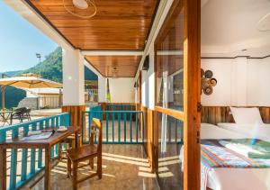 Habitación con balcón, cama y mesa. en Sabaidee Nam Ou River View, en Nongkhiaw