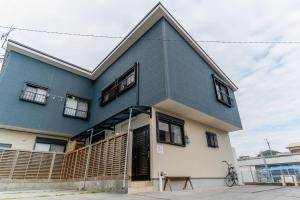 a blue house with a gambrel roof at Good Stay Apartment in Nichinan